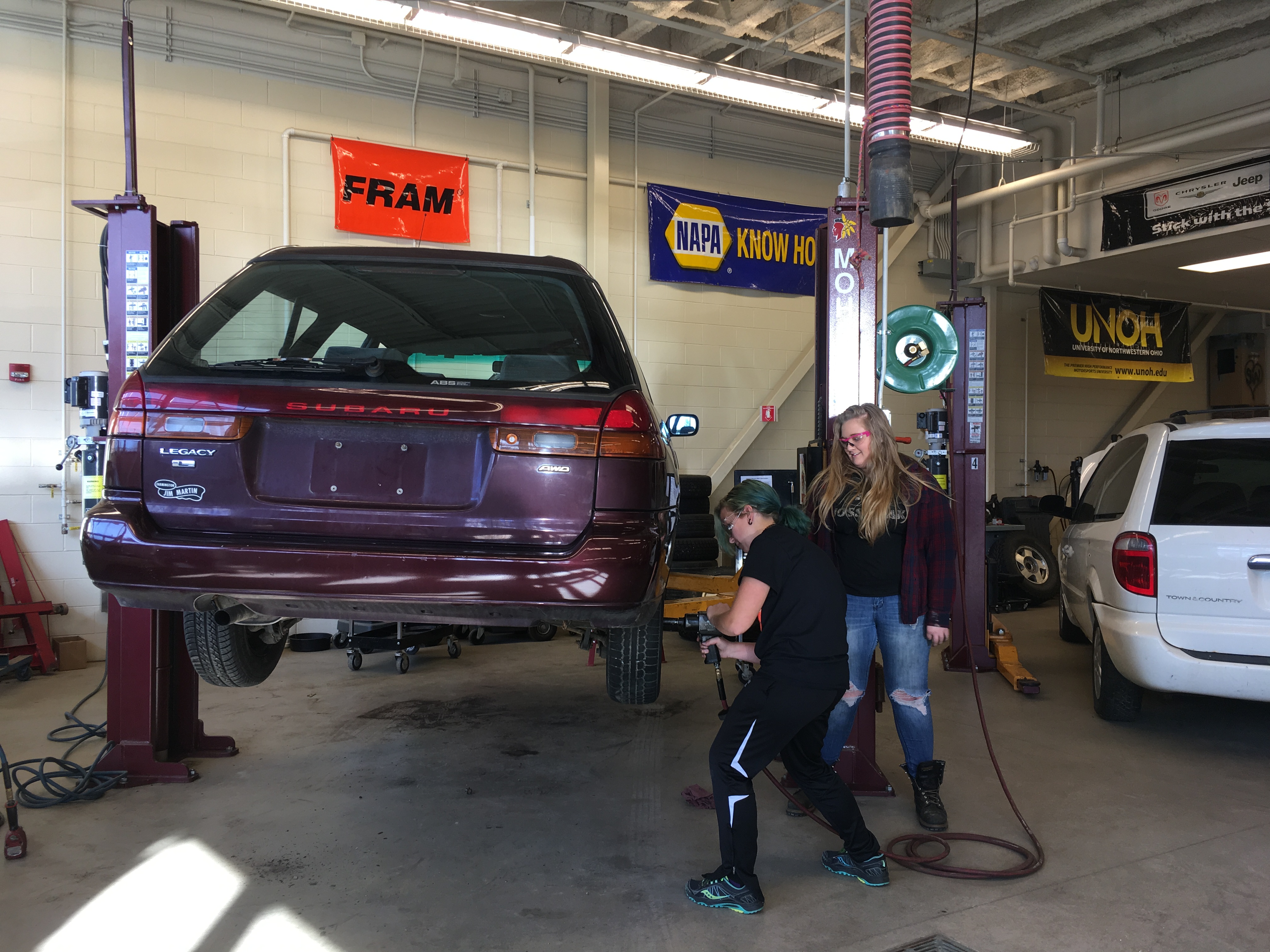 Two Totally Trades participants removing a car tire