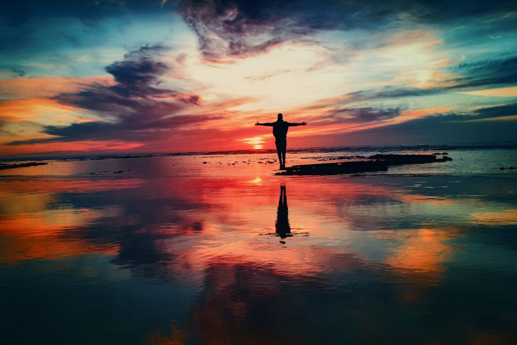 Person watching the sunrise with arms in the air
