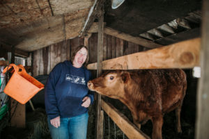 Lisa with her cow in a barn