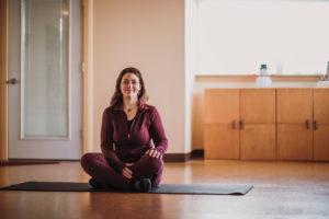 Sara sitting on yoga mat in her studio