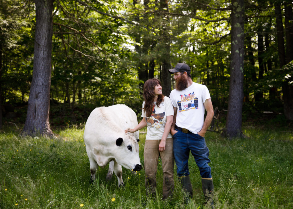 Owners of Apple Creek Farm standing with a cow in the woods