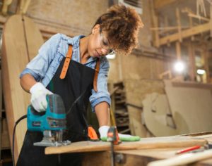 woman using power tool, constructing with wood