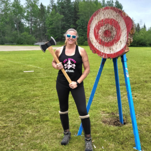 Photo of timber sports company athlete with axe in front of large target in a field