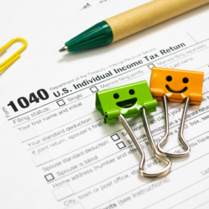 photo of tax form, pen and paper clips with smiles drawn on them