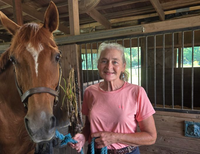 photo of Michelle Coad in her barn with a brown horse