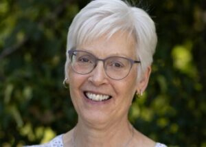 Kim has short silver hair and wears glasses