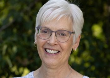 Kim has short silver hair and wears glasses